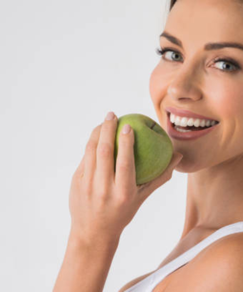 Fiatal nő egy zöld almába harap